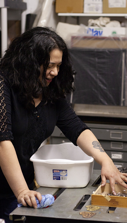 Woman reaching into a kiln to grab fresh ceramic work