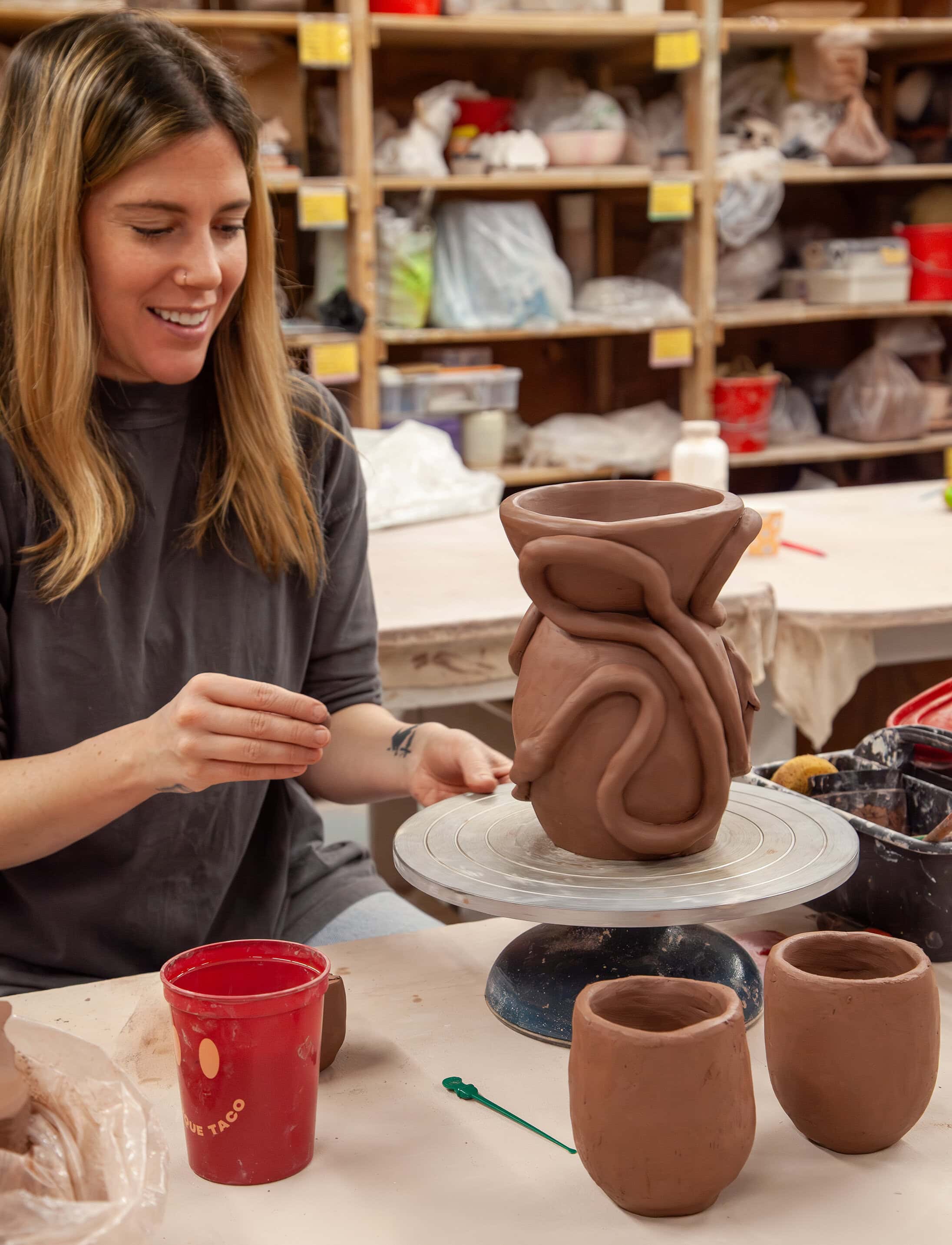 Smiling student adds a 3D snake detail to their ceramic vase.