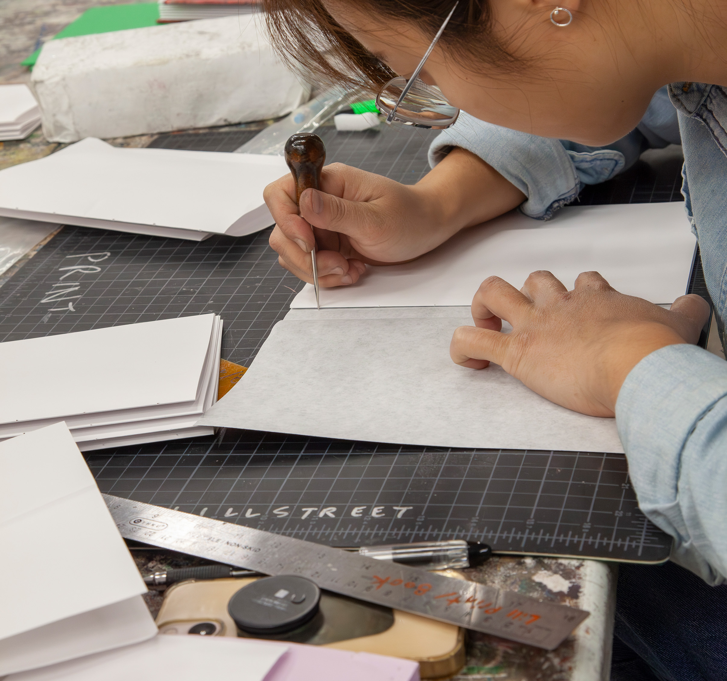 Student punching holes in the spine of a handmade book.