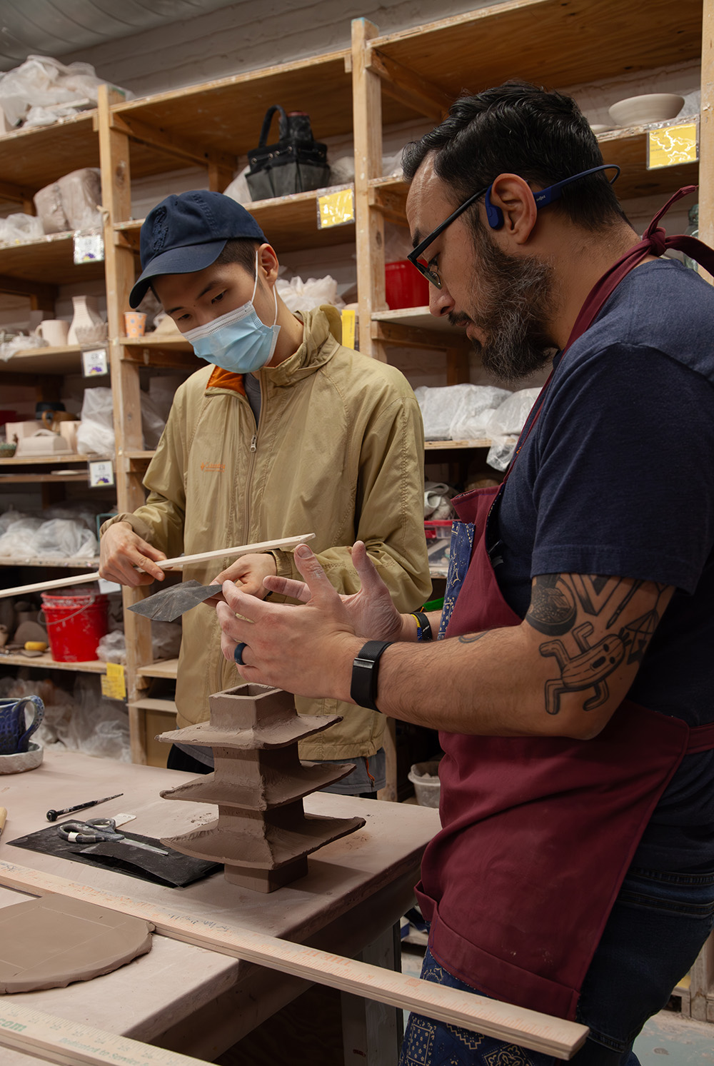Former Artist-In-Residence guiding a student in constructing a ceramic piece.